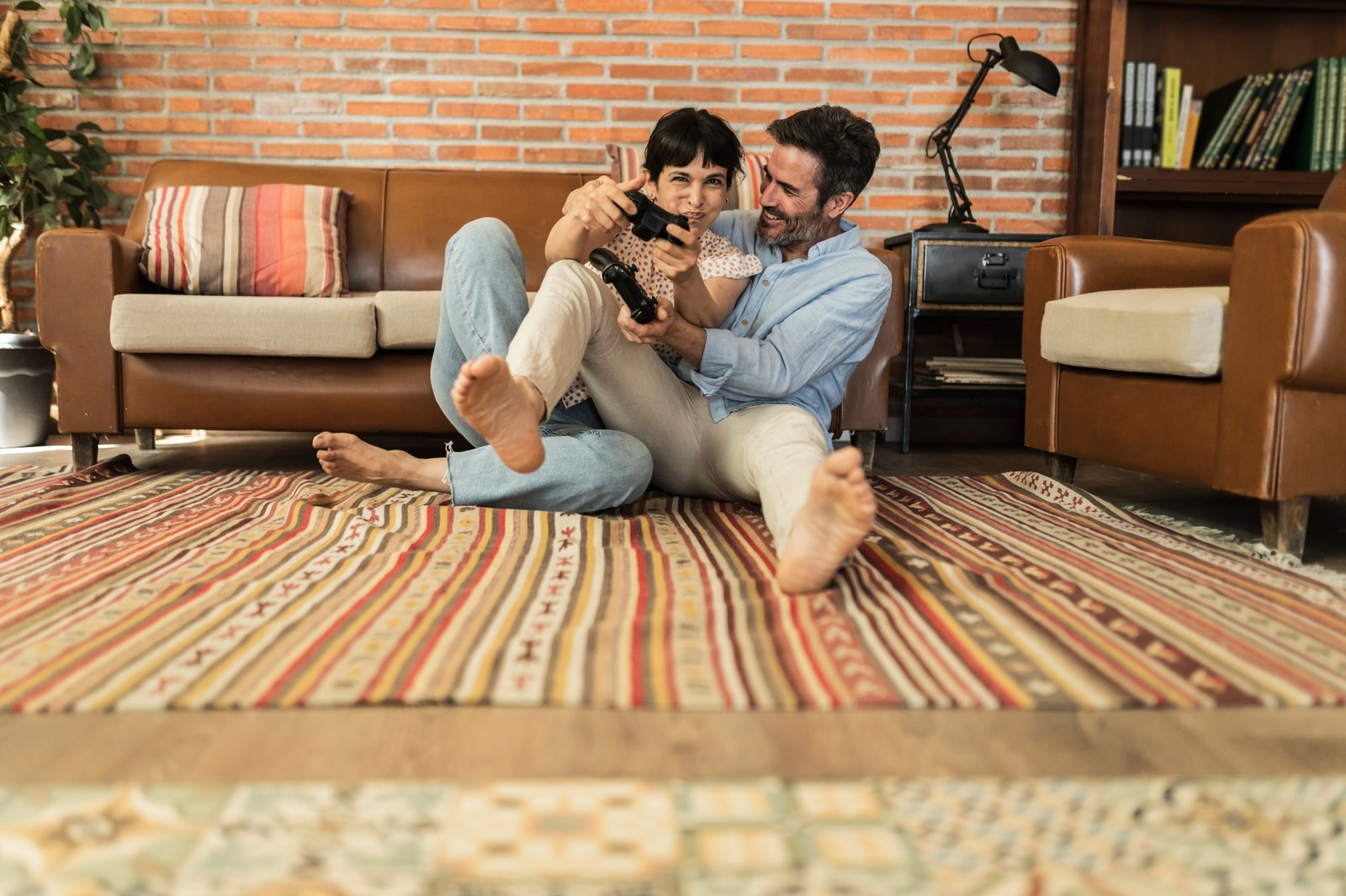 Middle aged hispanic couple sitting on the living room carpet playing video games